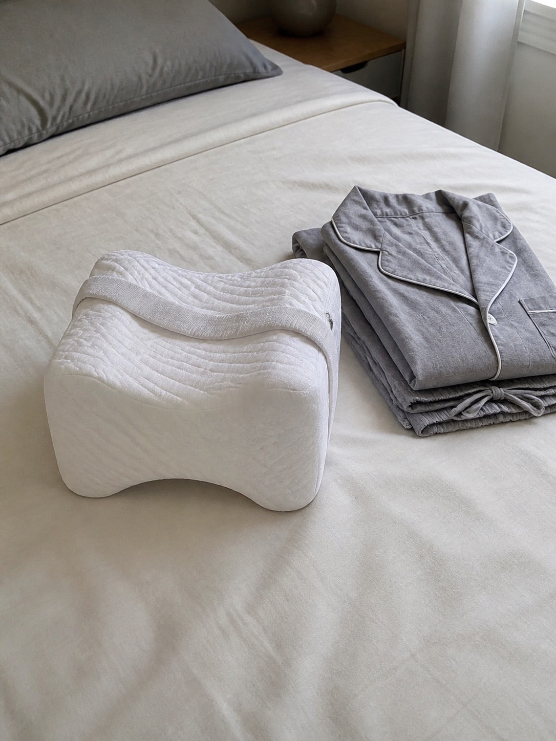AlignaFit knee pillow on a made bed