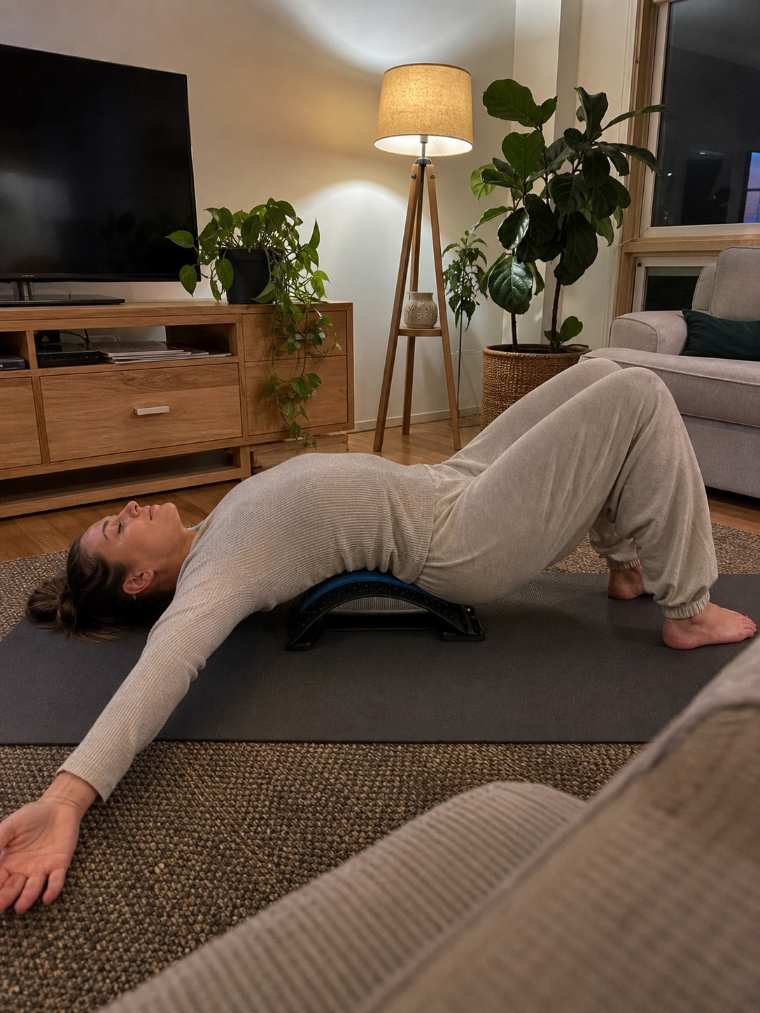 Lying on the AlignaFit lower back stretcher on a yoga mat at home
