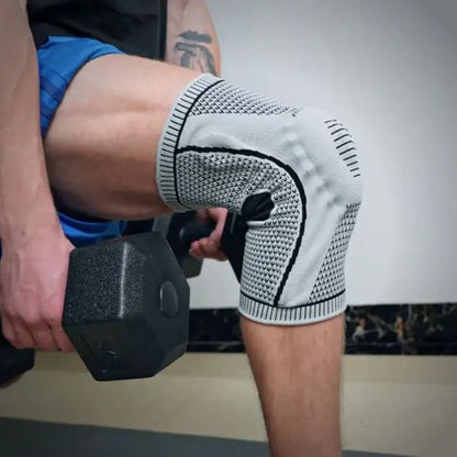Person holding a dumbbell wearing a grey knee brace with black patterns.