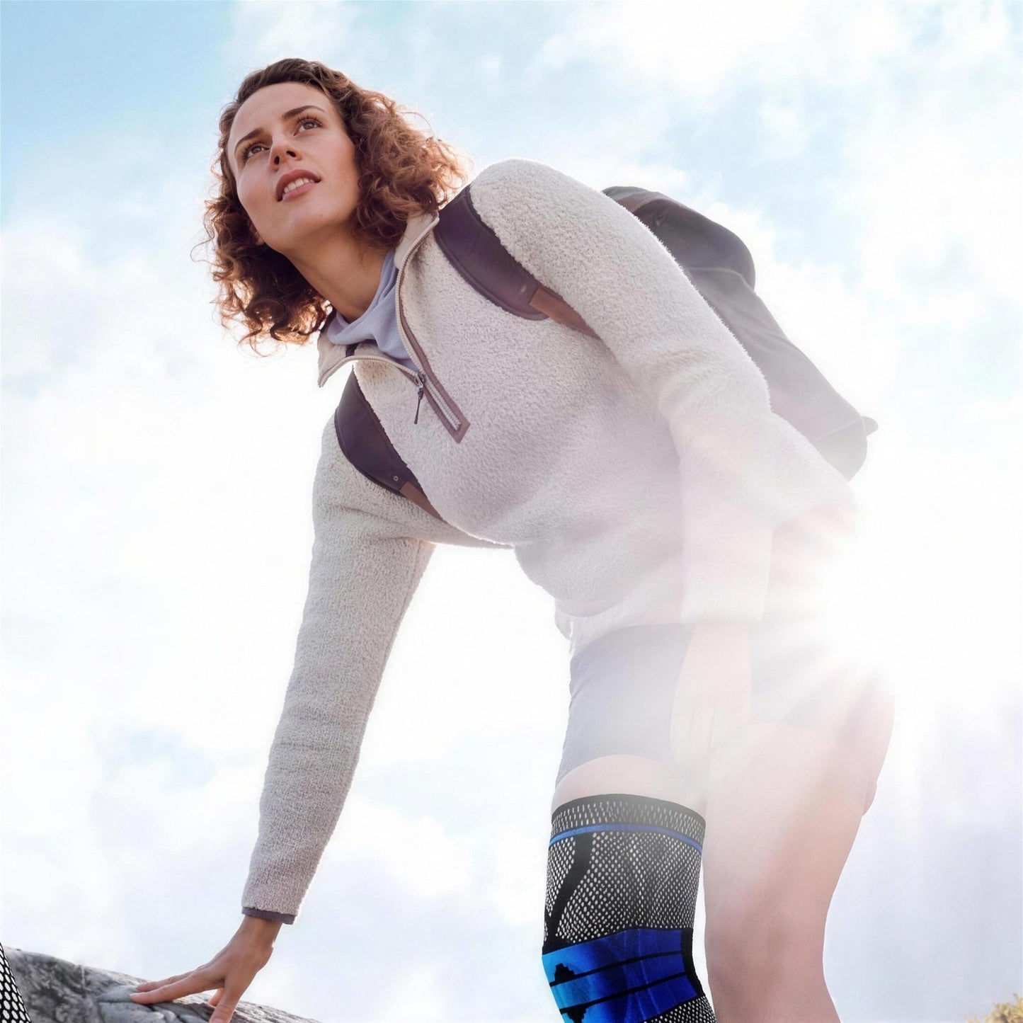 Woman hiking outdoors wearing the black AlignaFit knee compression sleeve